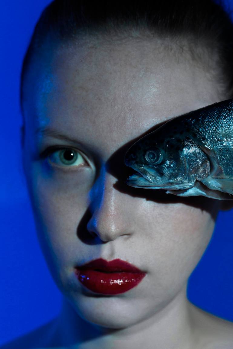 Nautical: a blue-toned portrait with a fish covering one eye